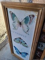 Full view of framed canvas showing three butterfly images and wooden frame