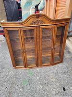 Front view of oak curio cabinet showing four glass doors, arched top and interior shelves
