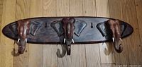 Full view of carved hardwood coat rack with three elephant head hooks