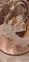 Close-up of glass swans on mirrored base highlighting gilt accents and glass texture