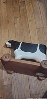 Side view of wooden cow toy showing wheels and paint wear on head