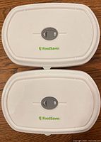Top view of two white sealing lids with FoodSaver logo