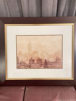 Front view showing sepia skyline print, mat, frame with gold trim