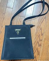 Front view showing GUESS logo plaque, front slip pocket and overall shape