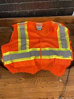 Front view of orange mesh vest with reflective stripes