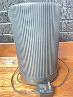 Front view of black vertical-ribbed Jafanoa JP100 air purifier with attached AC adapter