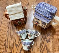 Front view of two cottage teapots and three floral teacups