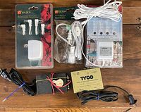Front view of lot showing packaged Lemax adapters, bagged cord set, Tyco transformer and two black transformers