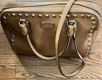 Front view showing studs, handles, detachable strap and logo plate