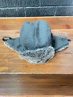 Overall view of charcoal trapper hat showing faux-fur trim and earflaps