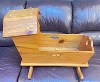 Side view of wooden rocking doll cradle on rocking base