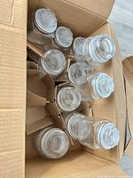 Box containing eleven clear glass jars with lids separated by cardboard dividers
