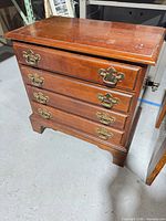 Front view of 4-drawer wooden night stand showing drawer pulls and bracket feet