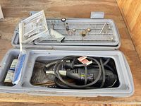 Open toolbox showing Dremel rotary tool, flexible shaft and accessory tray with multiple bits