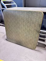 Full view of folded square table leaning upright