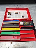 Full kit in open red case showing stones, clamp, oil, instructions