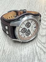 Angled view showing dial, bezel markings, leather strap and rivets