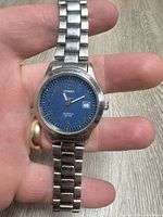 Front view showing blue dial, numerals, date window, bracelet