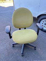 Front view of green fabric swivel office chair showing seat, backrest, arms, and base with casters