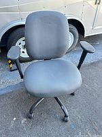 Front view of grey fabric office chair with armrests and four-star caster base