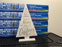 Four boxed Emerald lighted tree stakes behind wooden tree sign