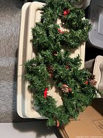 Two green artificial garland loops with pinecones and red ribbon accents