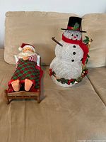 Sleeping Santa and lighted Frosty side by side on couch
