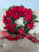 Front view of full wreath showing poinsettias, foliage and plaid bow