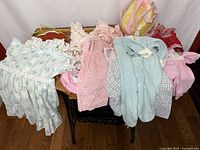 Overview of assorted doll clothing laid on bench