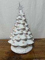 Front view of white ceramic Christmas tree showing bulbs and star