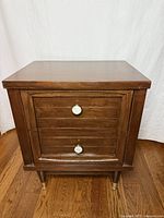 Front view of walnut two-drawer side table showing drawer fronts and brass-marble pulls