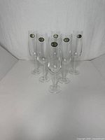 Front view of all six clear crystal flutes standing upright with stickers visible