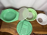 All six Tupperware pieces laid out: multi-server bowl, strainer-slicer insert, two gelatin mold bases, translucent seal, star insert