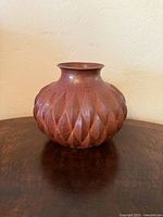 Front view of hammered copper vase showing fluted lobes and patina