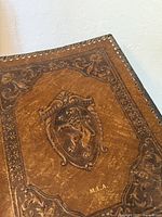 Embossed lion crest and initials on brown leather cover