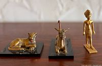 Three Metropolitan Museum of Art Egyptian figurines displayed on wood surface