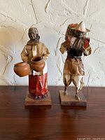 Front view of both papier mâché figurines on wood bases
