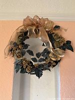 Full view of wreath hanging, showing bow, leaves, flowers and berries