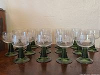Fifteen Luminarc Roemer glasses on wooden surface, front angled view