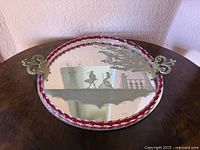 Full view of Murano mirrored glass tray showing etched romantic scene and red-rimmed edge