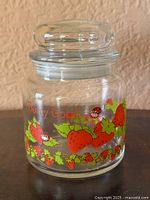 Front view of clear glass canister with lid and strawberry graphics