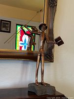 Full view of brass Don Quixote sculpture on stone base in front of mirror