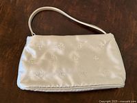 Full view of silver handbag front with handle visible