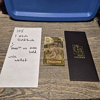 Goldback note with handwritten lot info slip and sleeve visible