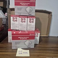 Stack of nine sealed Makrite L-188 N95 respirator boxes with note