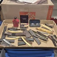 Tray showing straight razors, hones, strop handle, spectacles, AutoStrop case, red tin