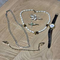Full lot view: wristwatch, beaded necklace, chain necklace, two brooches