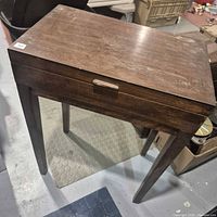 Dark stained wooden lift-top chest on tapered legs, closed