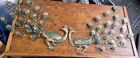 Both metal peacock wall sculptures on wooden surface