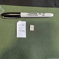 Full view of 1 g silver bar alongside marker for scale